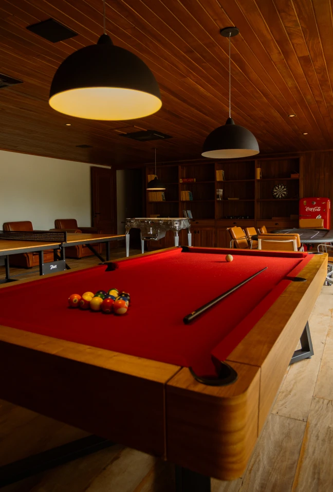 Sala de jogos com mesa de sinuca, ping pong, pebolim e refrigerador Coca-Cola.